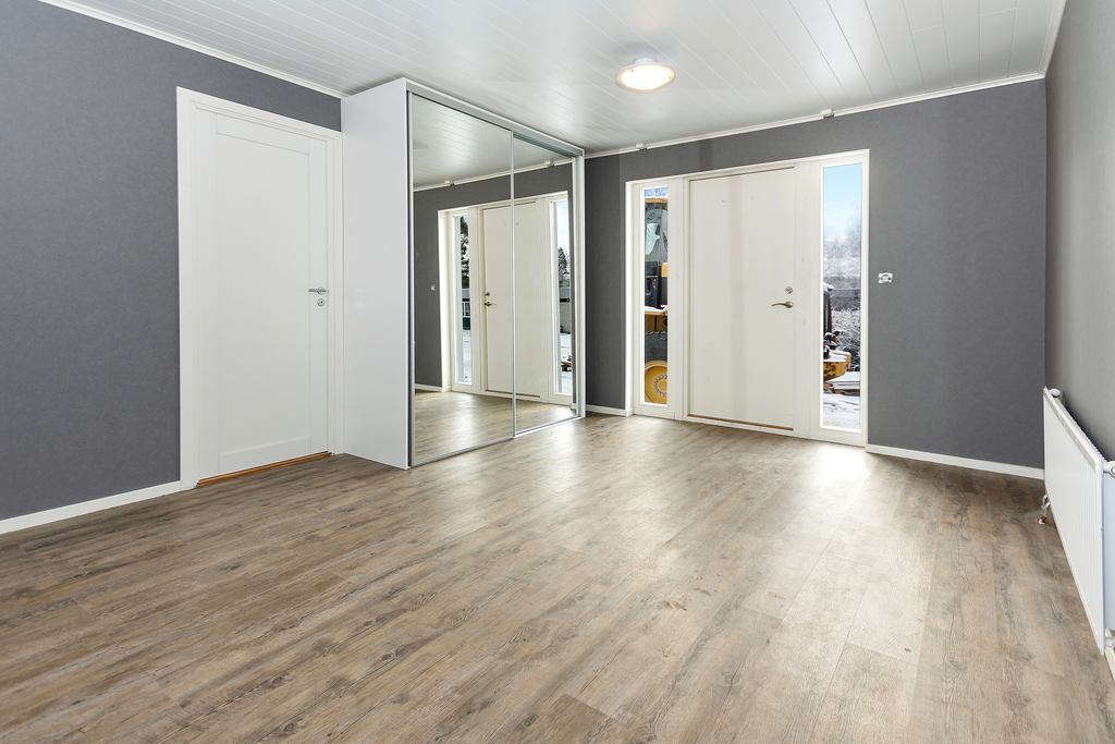 Välkomnande hall med mycket plats och trevligt ljusinsläpp från fönster på båda sidor om dörren.